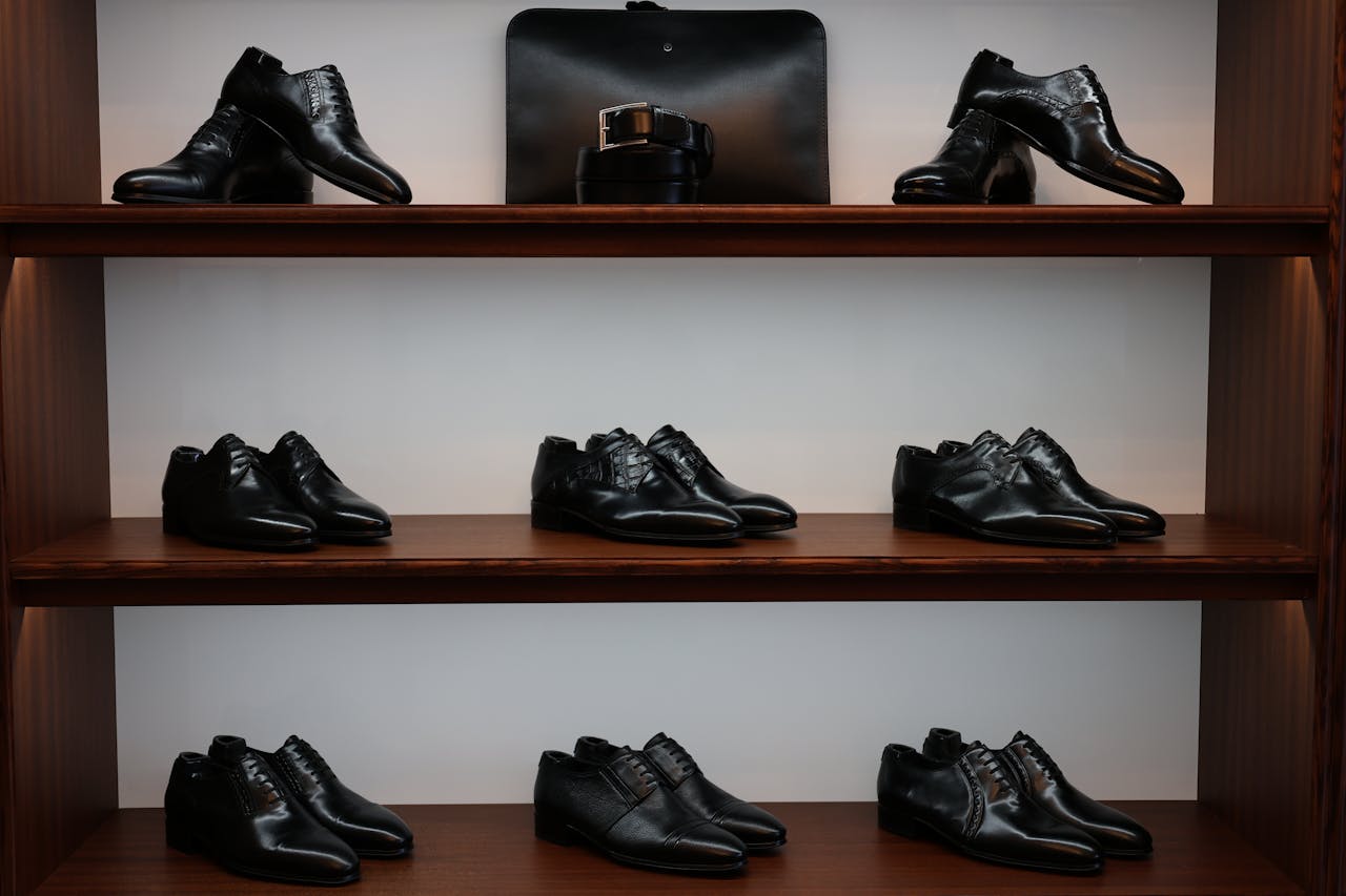 about-us-01 A stylish display of black leather shoes and accessories on wooden shelves in a store.